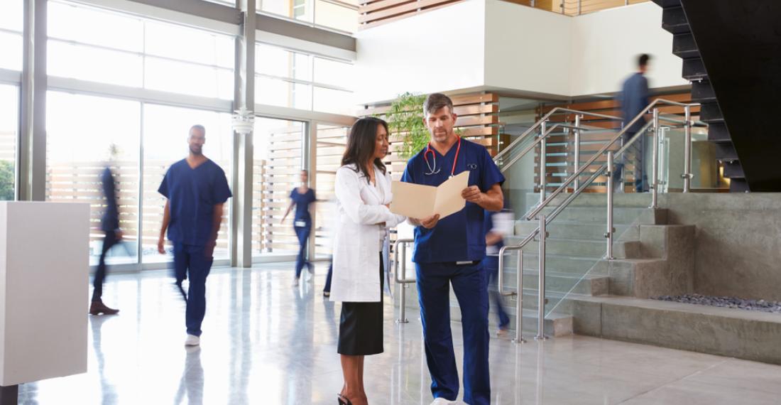 Doctors speaking to each other in a hospital, looking over a file folder.